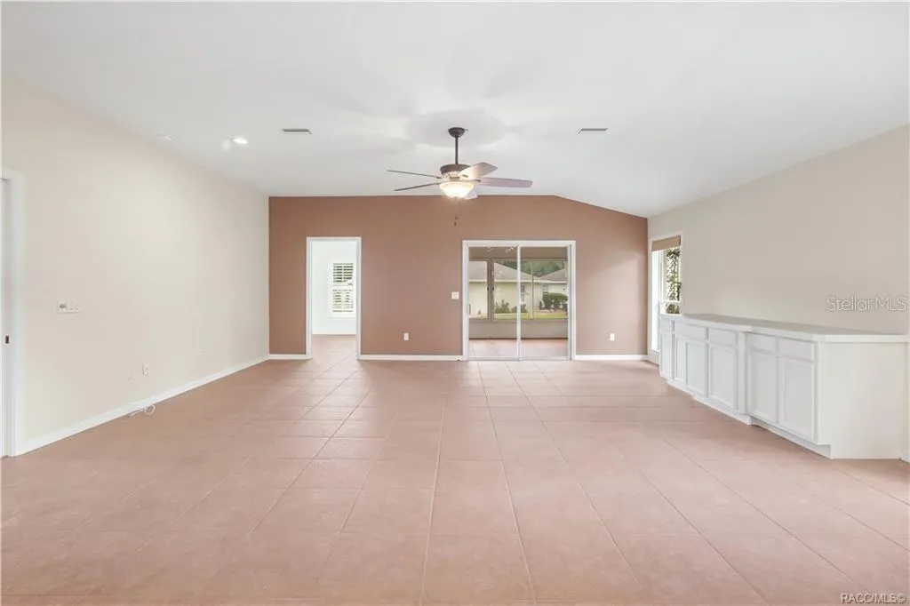 Living Room – Generously sized main living area with expansive tile flooring, ceiling fan &amp; plenty of room to create multiple conversation or entertainment areas. Sliding glass doors extend the towards the Florida room and flex room /4th bedroom.