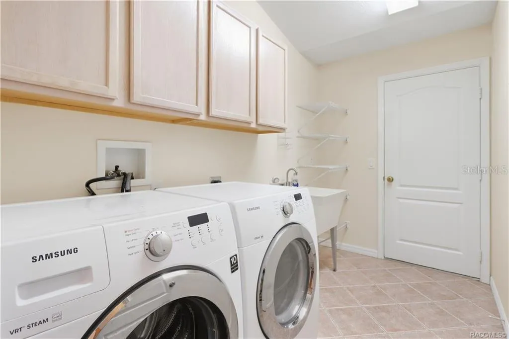 INDOOR LAUNDRY ROOM – Dedicated interior laundry room with washer &amp; dryer, utility sink, upper cabinetry, additional wire shelving &amp; tile flooring.