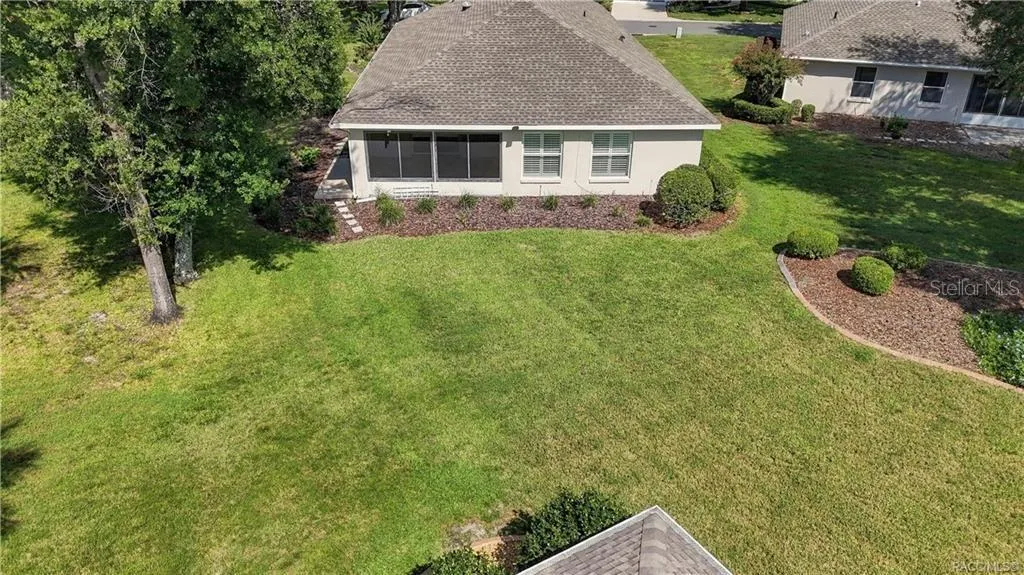 BACKYARD – Elevated view highlighting the spacious open backyard (common area), established trees, landscaped beds &amp; rear exterior of the home.