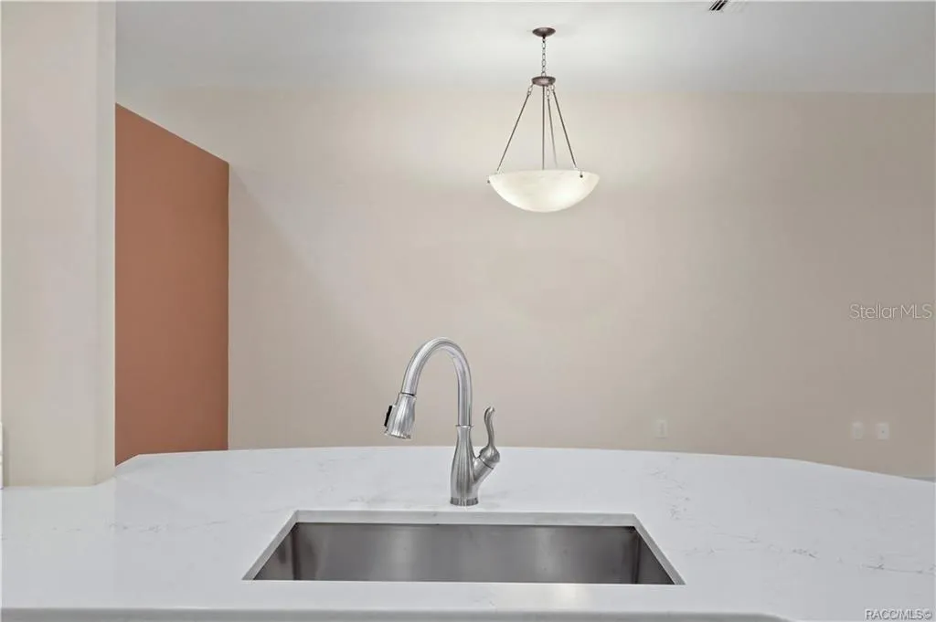 PENINSULA / SINK – Large quartz peninsula with an undermount stainless-steel sink &amp; pull-down faucet creates a generous prep and serving area while maintaining an open view toward the adjoining living and dining spaces.