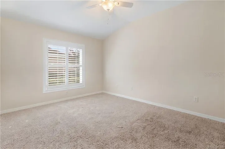 BEDROOM 3 – Spacious bedroom featuring ceiling fan &amp; window with plantation shutters.