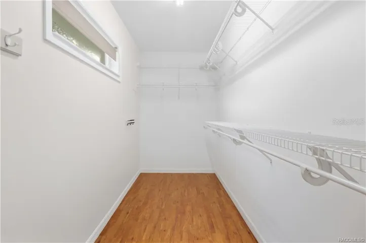 PRIMARY WALK-IN CLOSET – Generously sized walk-in closet with extensive wire shelving &amp; hanging space on multiple walls, plus a window for natural light.