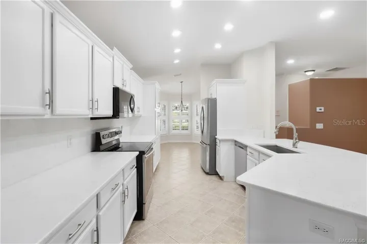 REMODELED KITCHEN – Bright, updated kitchen with crisp white cabinetry, quartz countertops, stainless-steel appliances, recessed lighting &amp; a large peninsula that provides additional prep space while keeping the kitchen connected to the living area.