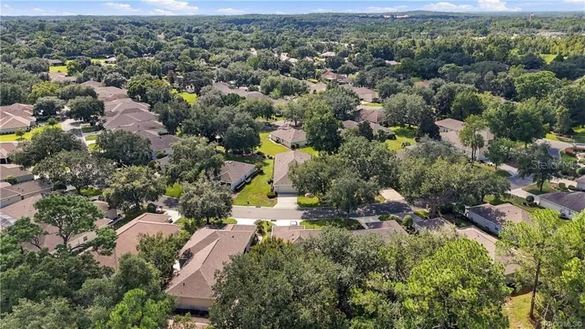COMMUNITY AERIAL – Wide aerial perspective showcasing the home’s neighborhood setting with tree-lined streets, established homes &amp; expansive surrounding greenery.