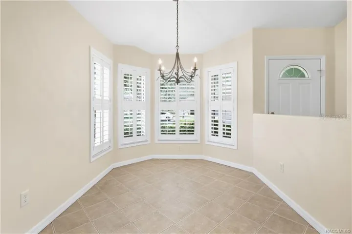Kitchen Nook Light-filled dining area featuring diagonal-set tile flooring, a decorative chandelier &amp; an impressive grouping of windows finished with plantation shutters—an inviting setting for everything from morning coffee to dinner with friends.