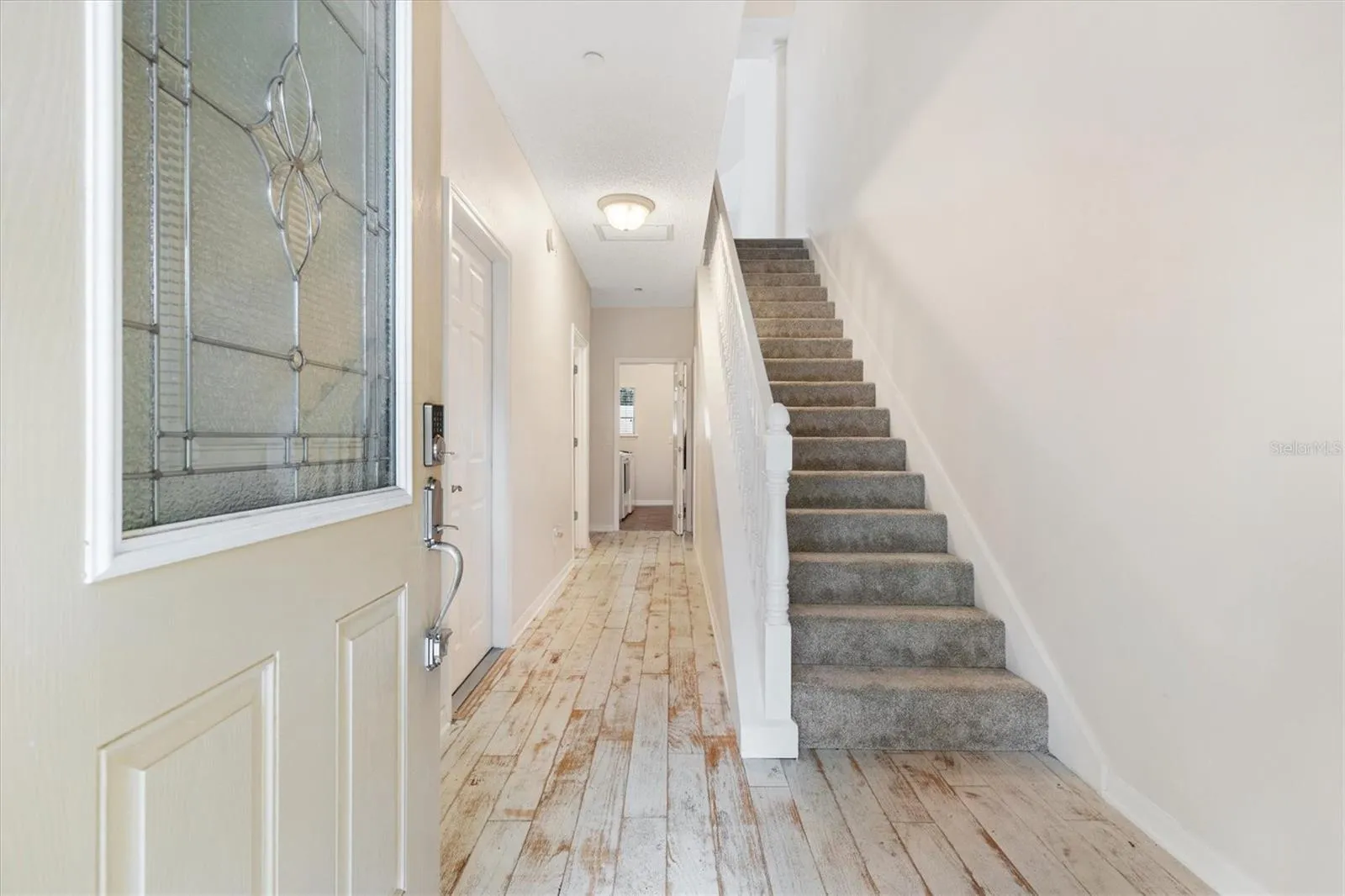 Foyer into 1st Floor w/ Distressed Engineered Wood Flooring. Carpet padded stairs.