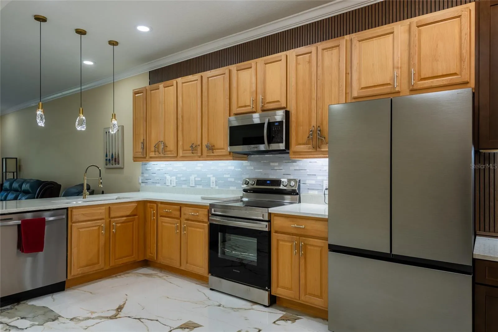Kitchen with tall cabinets, glass pendant lights and new appliances.