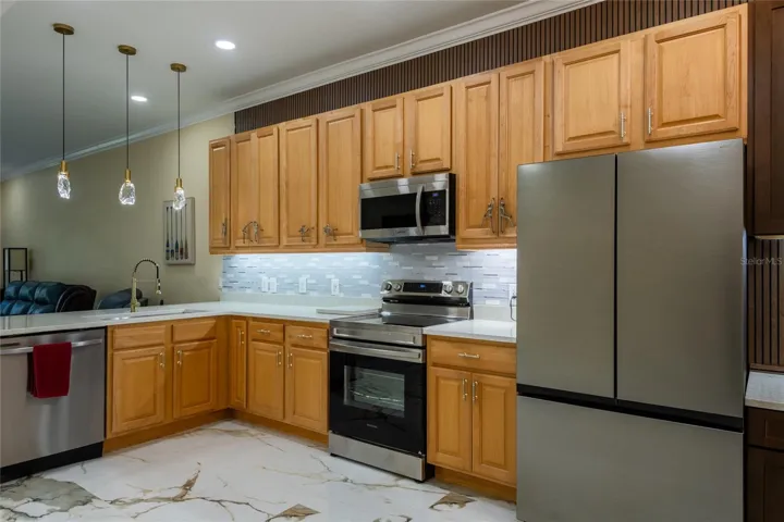 Kitchen with tall cabinets, glass pendant lights and new appliances.