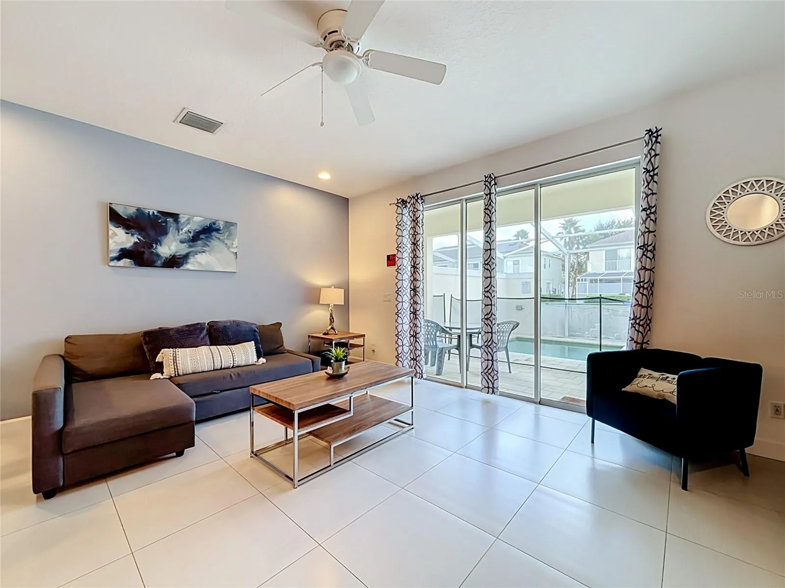 Living Room — Bright living space with large sliding glass doors bringing in natural light and connecting the interior to the screened pool deck.