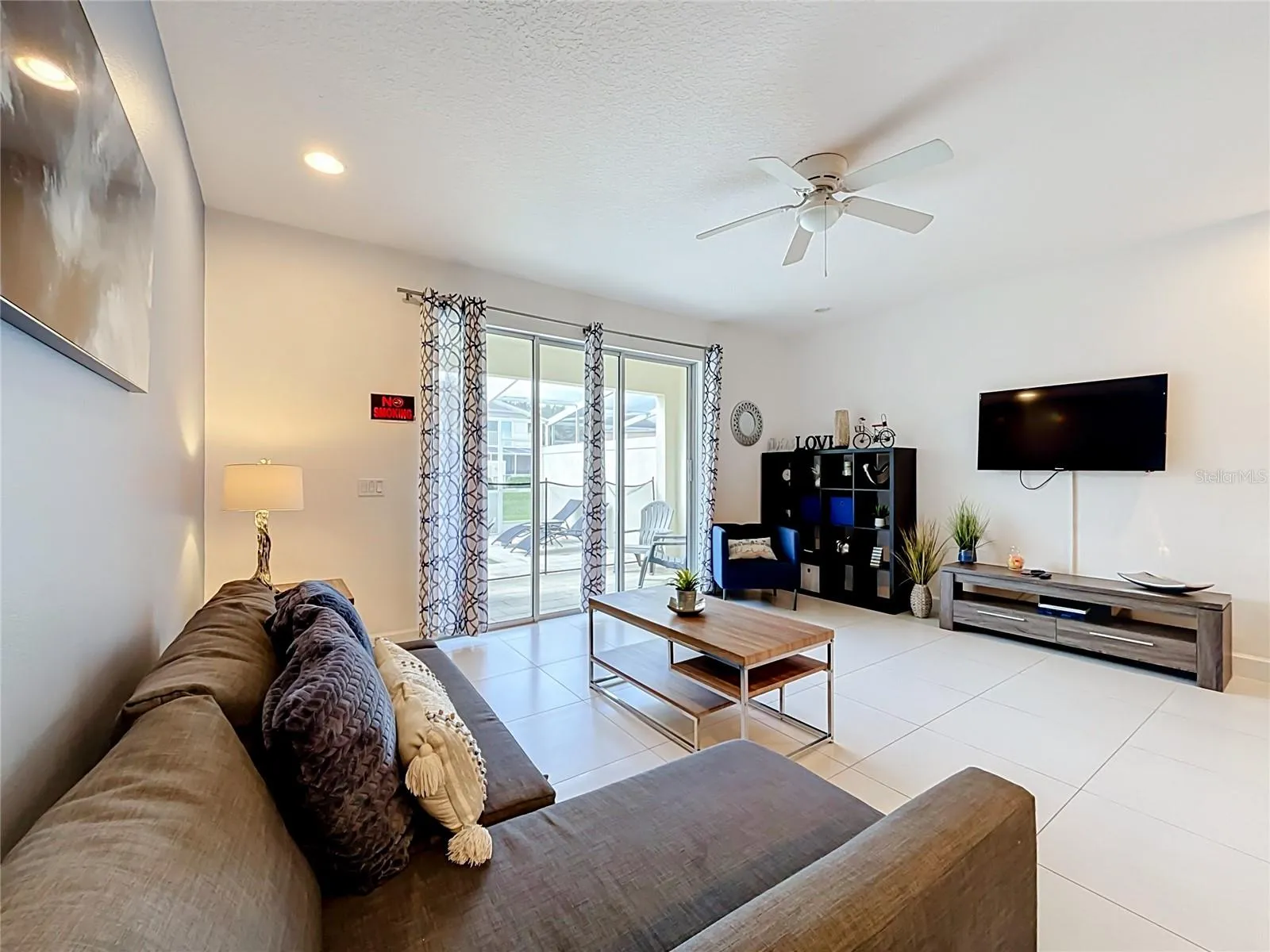 Living Room — Comfortable living area with tile flooring and sliding glass doors providing direct access to the private pool area.
