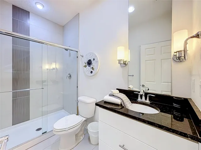 Downstairs En-Suite Bath — Private full bathroom serving the downstairs bedroom, featuring a walk-in shower and contemporary finishes.