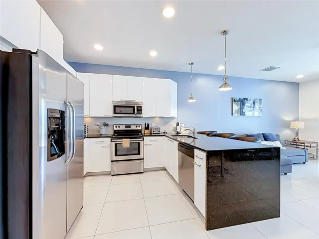 Kitchen — Spacious modern kitchen featuring high-gloss cabinetry, stainless steel appliances, and generous counter and storage space.