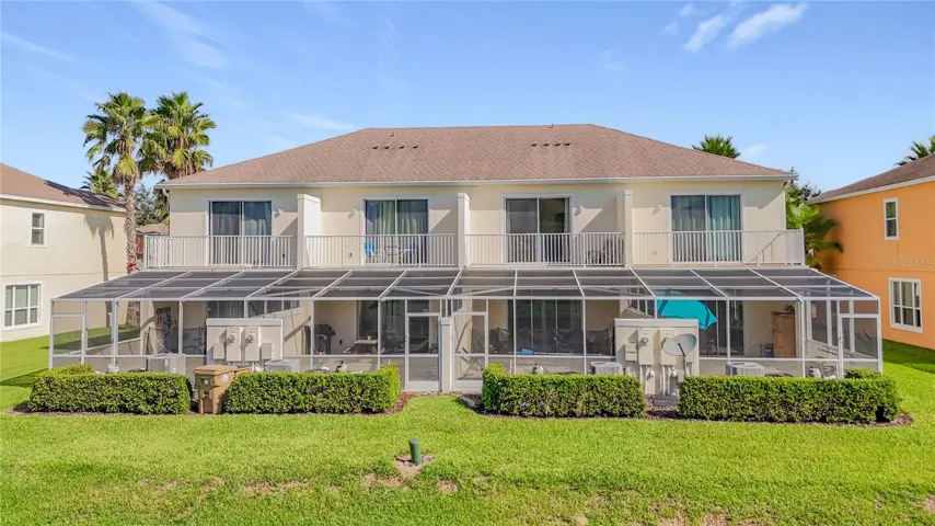 Rear Exterior — Rear view showcases the home's private pool enclosure, upstairs balcony, and desirable open setting overlooking the pond area.
