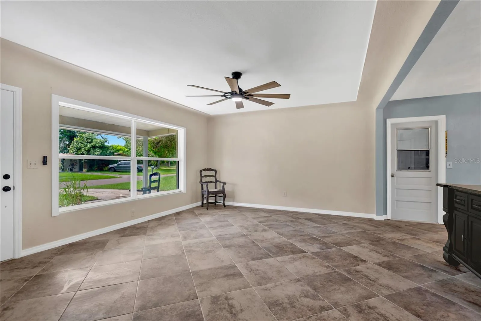 The spacious living room features an upgraded oversized window that fills the space with natural light, neutral paint, and a stylish new ceiling fan/light fixture.