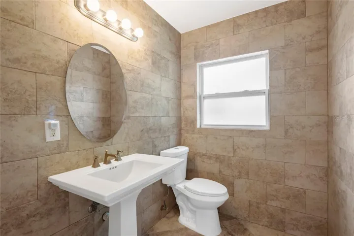 There is a half bathroom across the hall from bedroom #2 and has new pedestal sink, toilet, window and fixtures and has been tiled floor to ceiling.