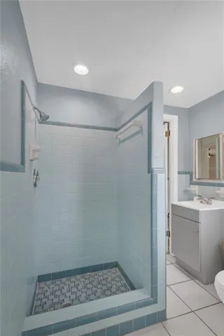 The spacious shower stall showcases the timeless charm of the original tile, beautifully preserved to highlight its nostalgic character and enduring appeal.