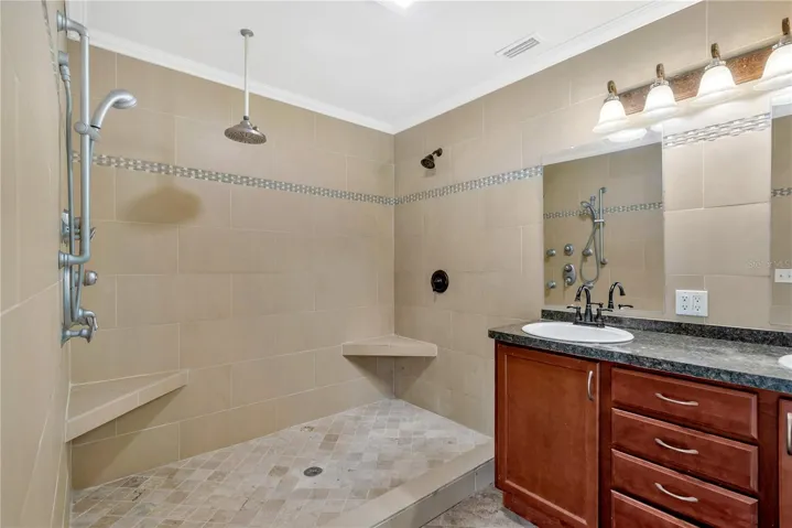 This custom-tiled shower features a central rain showerhead, additional showerheads, and a convenient removable handheld showerhead for a spa-like experience.