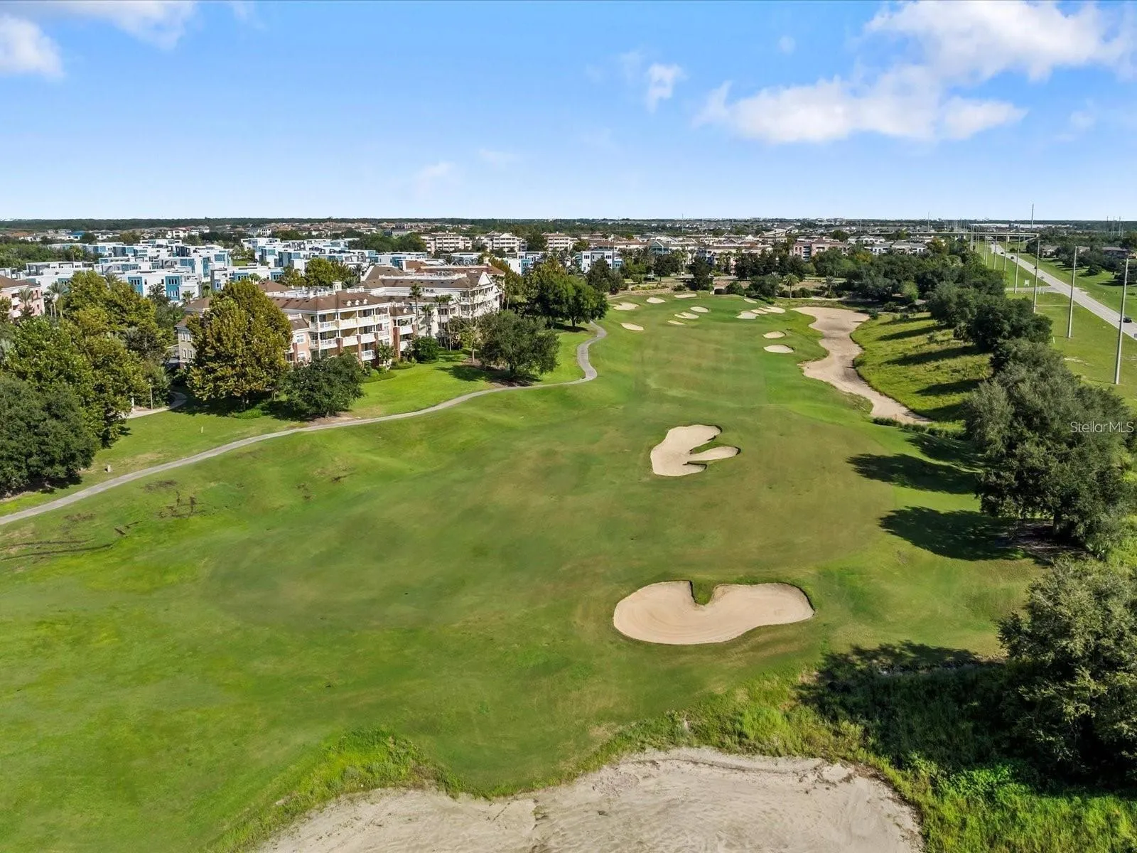 Aerial View of Golf Course &amp; Condos: Wide aerial perspective of the championship golf course fairway, sand hazards, paved cart paths, and adjacent residential condos.