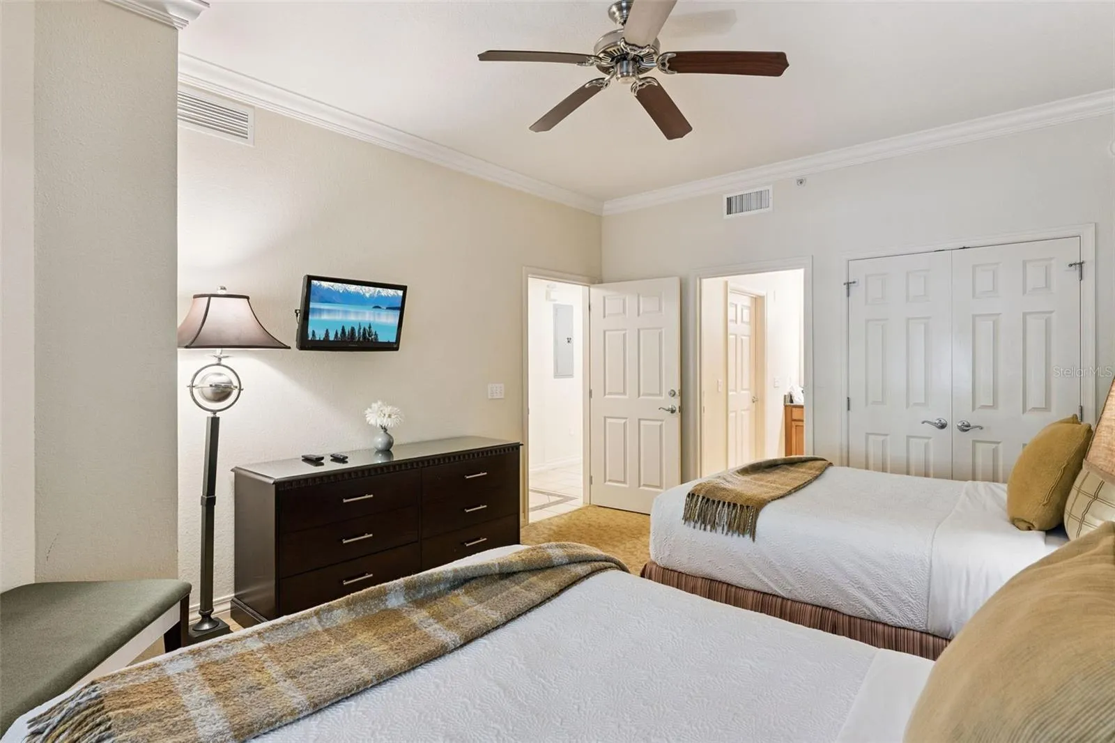 Double Bedroom Alternate View: Angle of the double guest room showcasing a matching dresser, wall-mounted TV, double bi-fold closet doors, and adjacent hallway access.