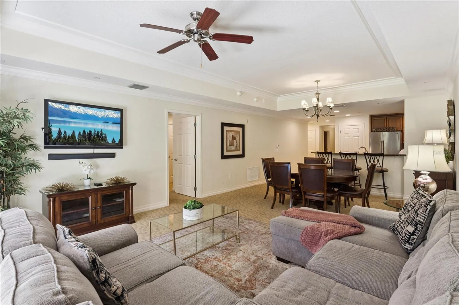 Open-Concept Layout: Spacious living and dining combination area seamlessly connecting to the kitchen, complete with tray ceiling accents and ceiling fans.