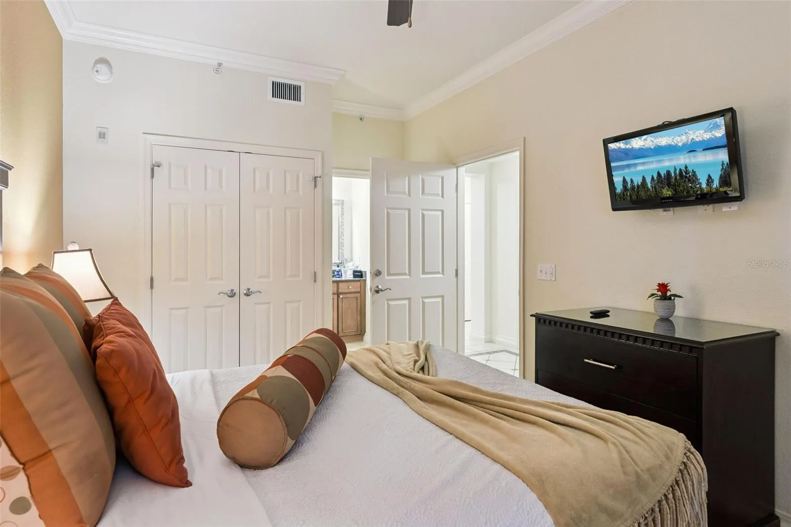 Bedroom: Comfortably sized bedroom offering crown molding, a wall-mounted flat-screen TV, double bi-fold closet doors, and direct access to a nearby bath.