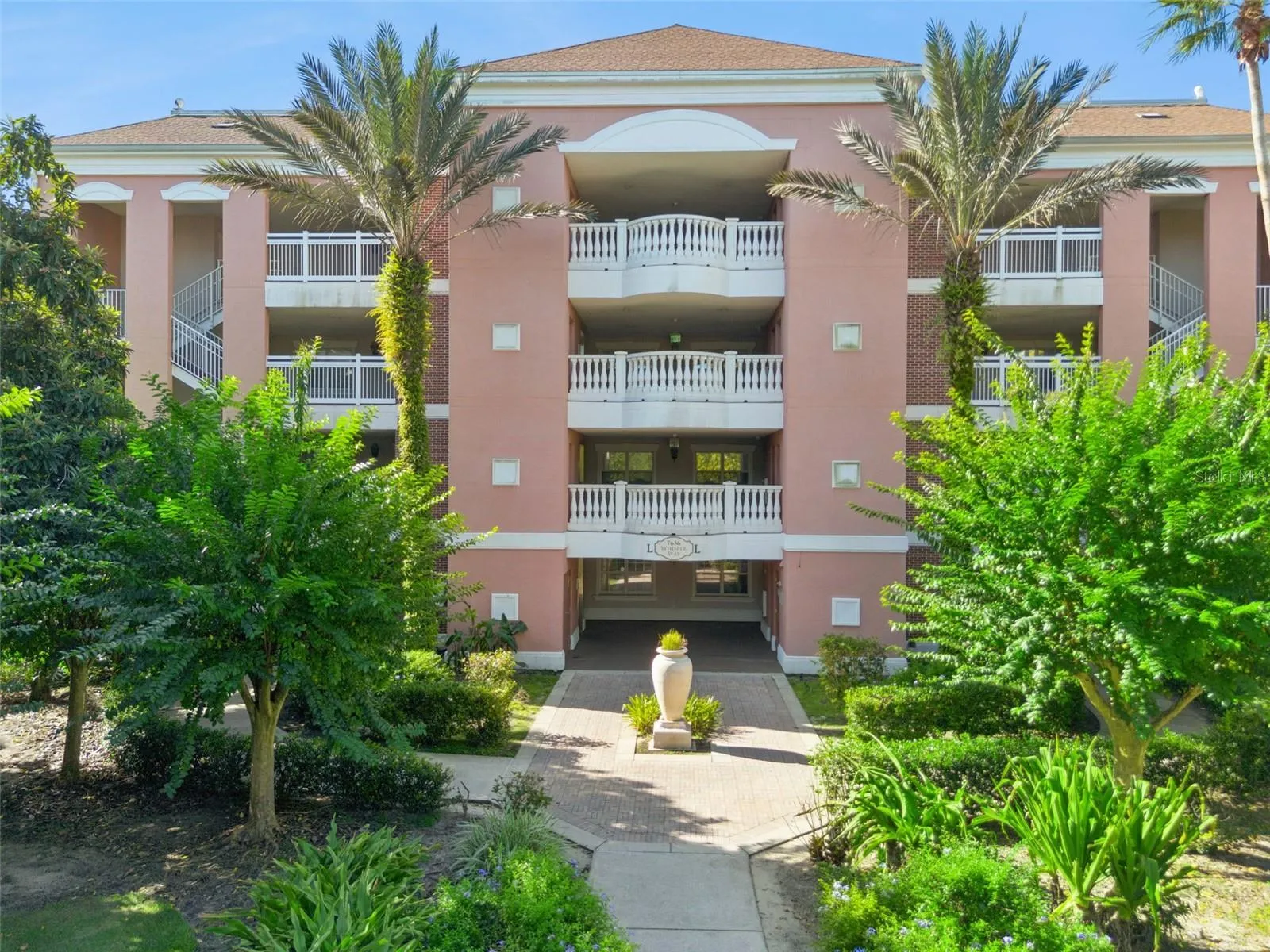 Building Exterior: Mediterranean-style exterior elevation featuring tropical palm trees, manicured landscaping, and a paver pathway leading to the main entrance.
