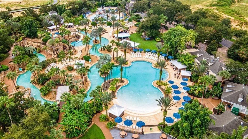 Aerial View of Water Park &amp; Resort Pool: High-angle drone view of the sprawling resort water park featuring a lazy river, zero-entry pool, water slides, and expansive lounge decks surrounded by tropical foliage.