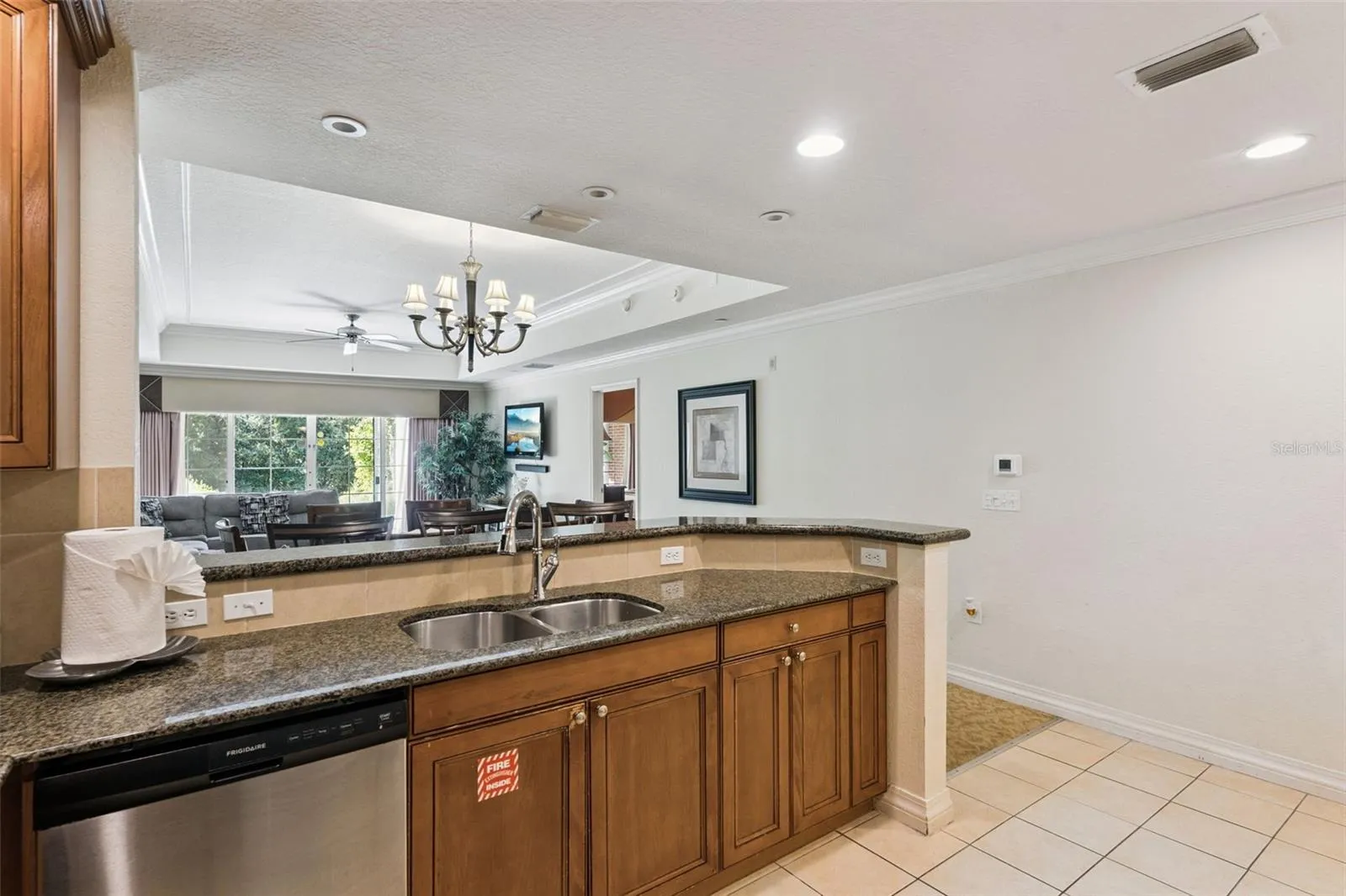 Kitchen Pass-Through Counter: Functional kitchen layout with rich wood cabinetry, durable granite countertops, an undermount double sink, and open views into the living space.