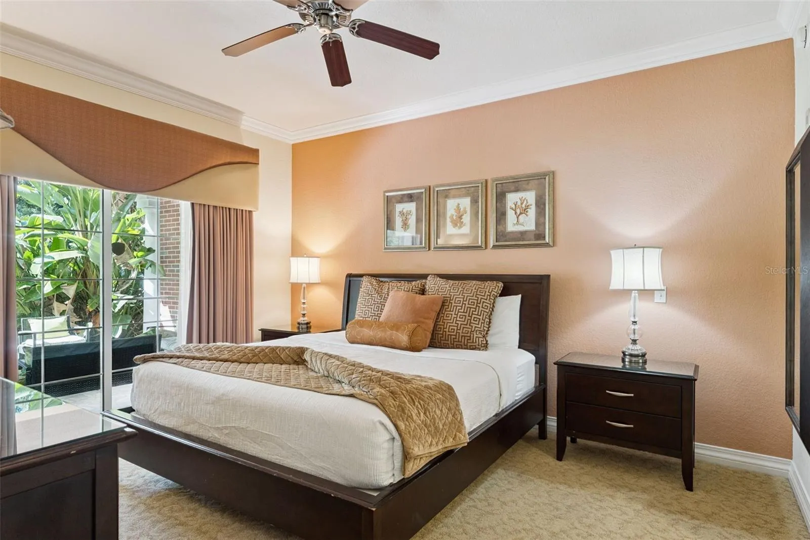 Primary Bedroom Alternate View: Primary suite showcasing a warm-toned accent wall, ceiling fan, nightstand space, and floor-to-ceiling glass sliders for convenient outdoor access.