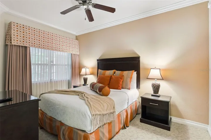 Guest Bedroom: Cozy guest bedroom complete with crown molding, a ceiling fan, dark wood furnishings, decorative window drapery, and warm neutral accent walls.