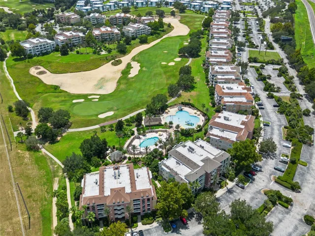 Resort Grounds &amp; Golf Course: Broad aerial overview featuring the resort pool area, adjacent golf course greens, manicured landscaping, and surrounding community.