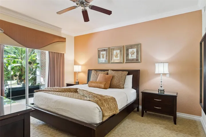 Primary Bedroom Alternate View: Primary suite showcasing a warm-toned accent wall, ceiling fan, nightstand space, and floor-to-ceiling glass sliders for convenient outdoor access.