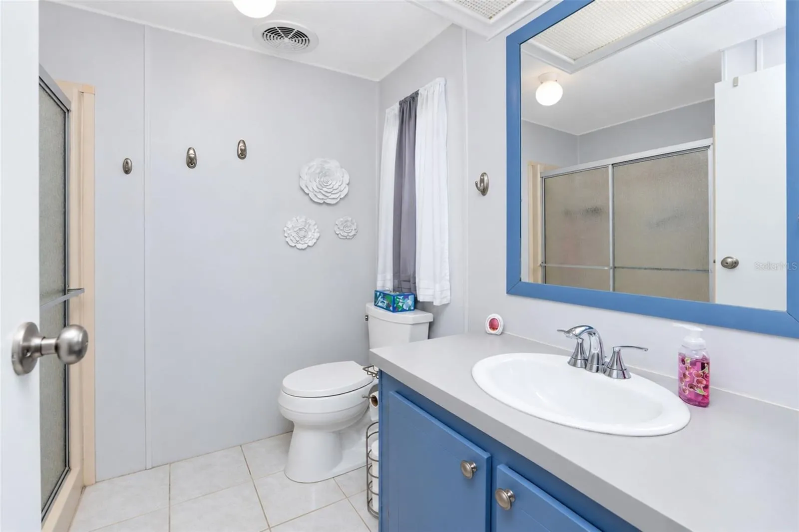 Primary bath has tiled flooring and step in shower with a door.