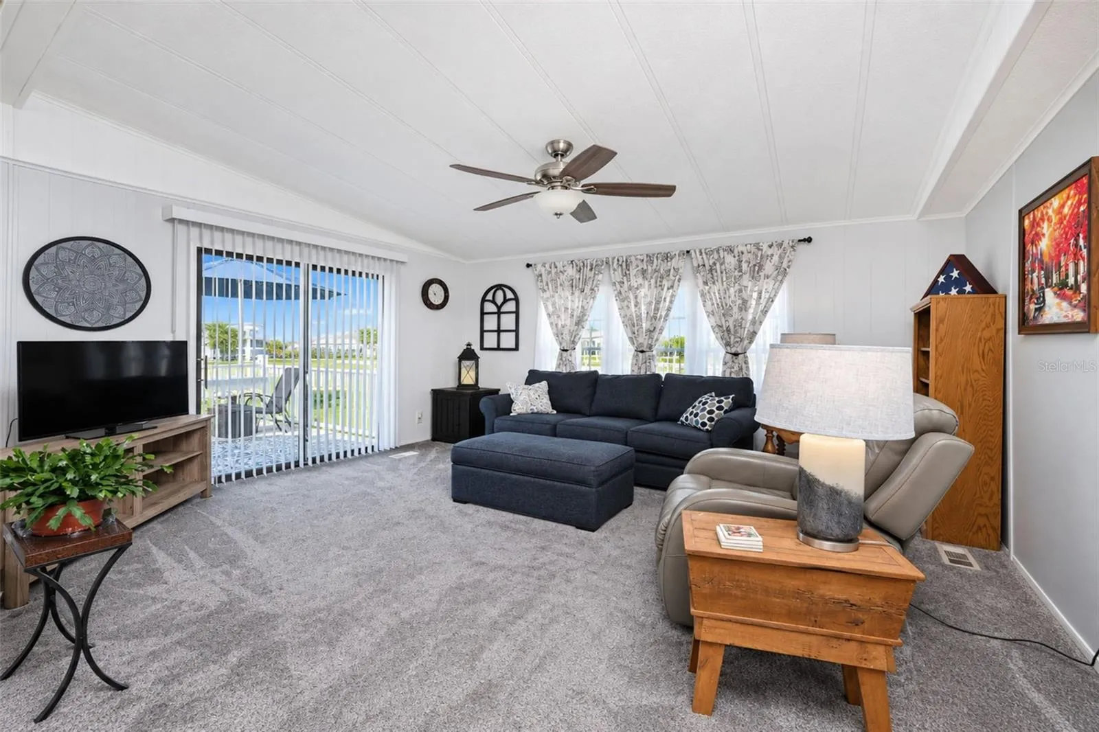 Living room has newer carpeted flooring, cathedral ceiling and ceiling fan