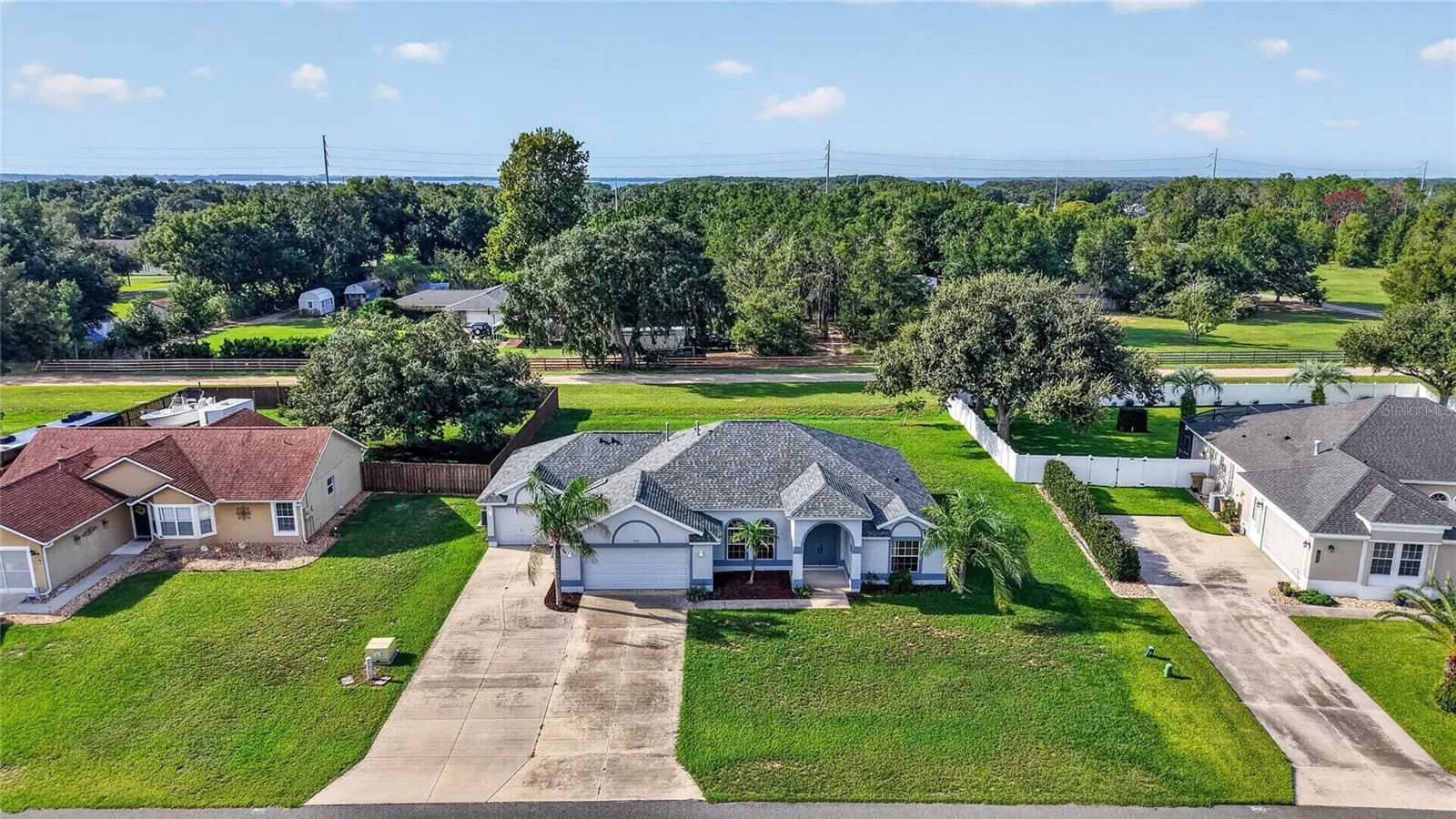 An aerial view highlights the home's spacious lot, expansive driveway, and dual-garage configuration.