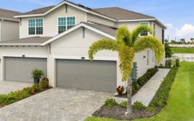 Beautifully landscaped front exterior with lush greenery and a picturesque water view.