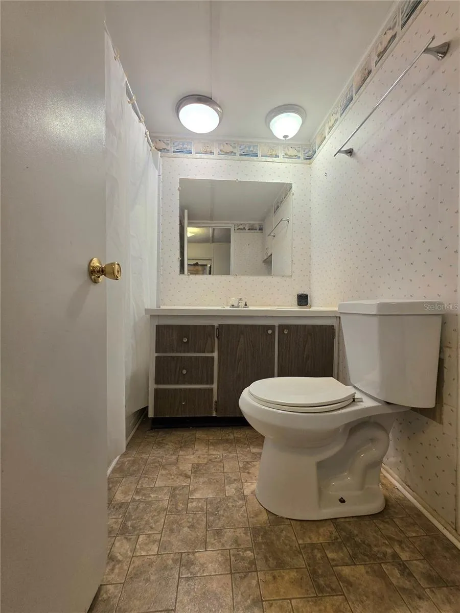 Bathroom features a bathtub with shower and vinyl flooring.