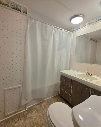 Bathroom features a bathtub with shower and vinyl flooring.
