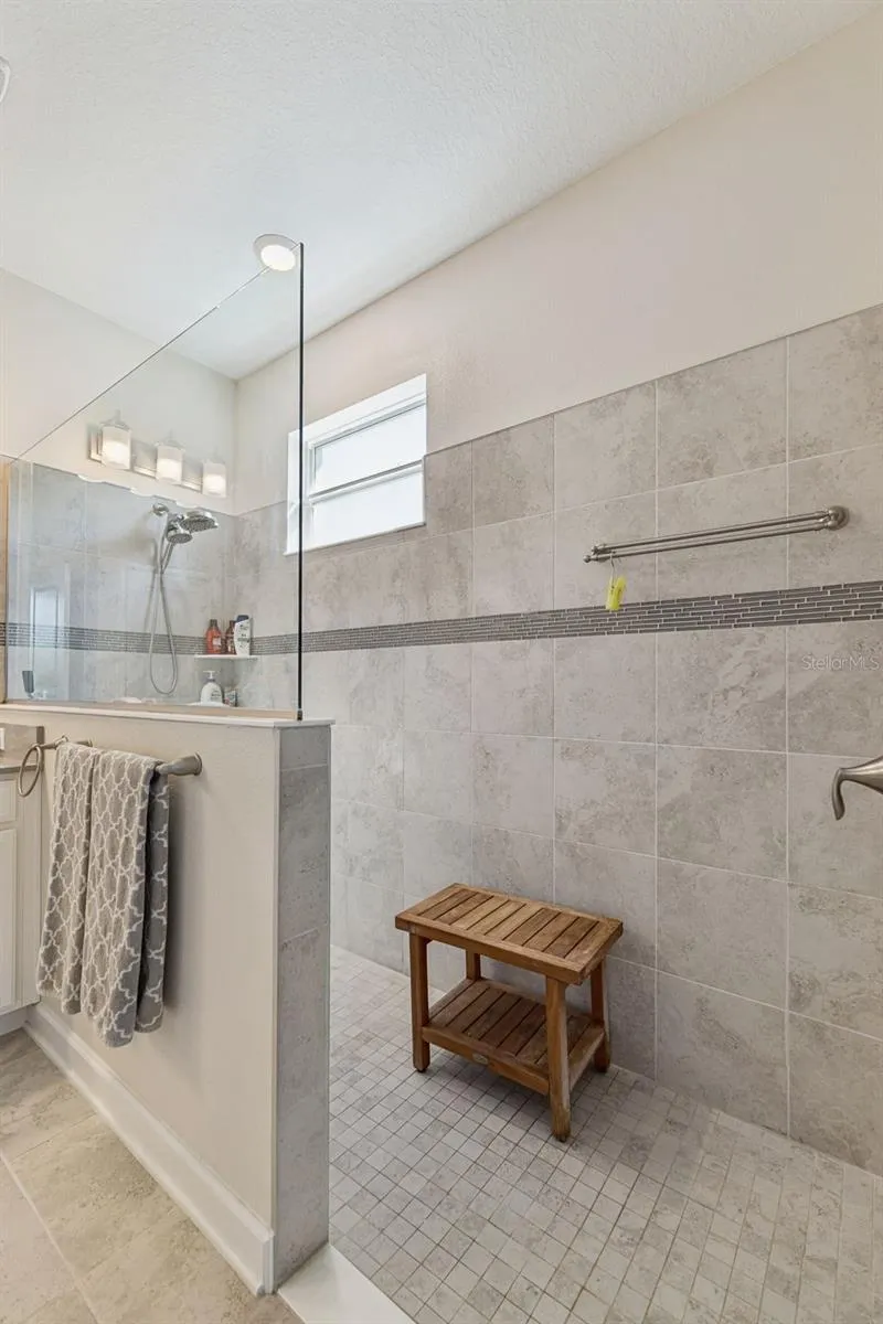 Handicap Accessible Tiled Shower adorned with Decorative Listello Tile and Glass Enclosure