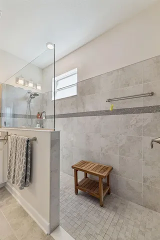 Handicap Accessible Tiled Shower adorned with Decorative Listello Tile and Glass Enclosure