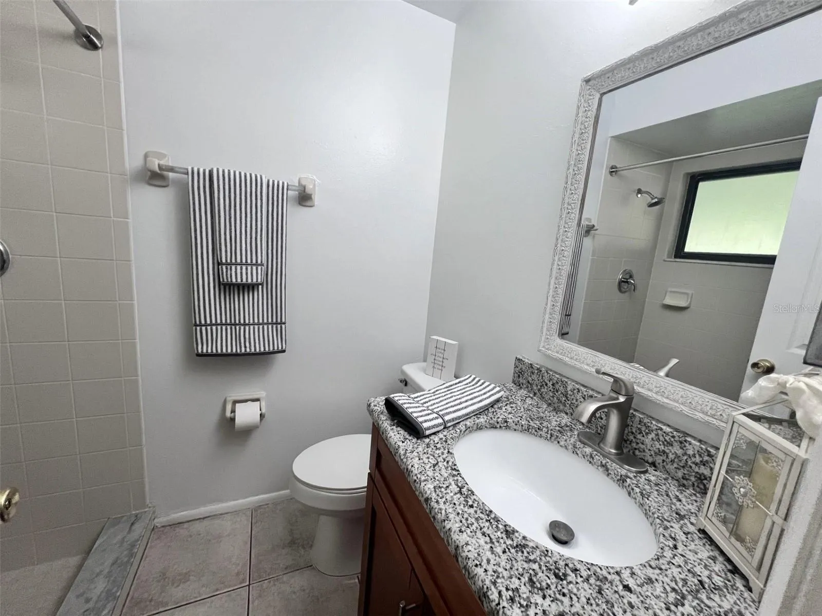 Primary bathroom with updated vanity, granite countertop and walk-in shower