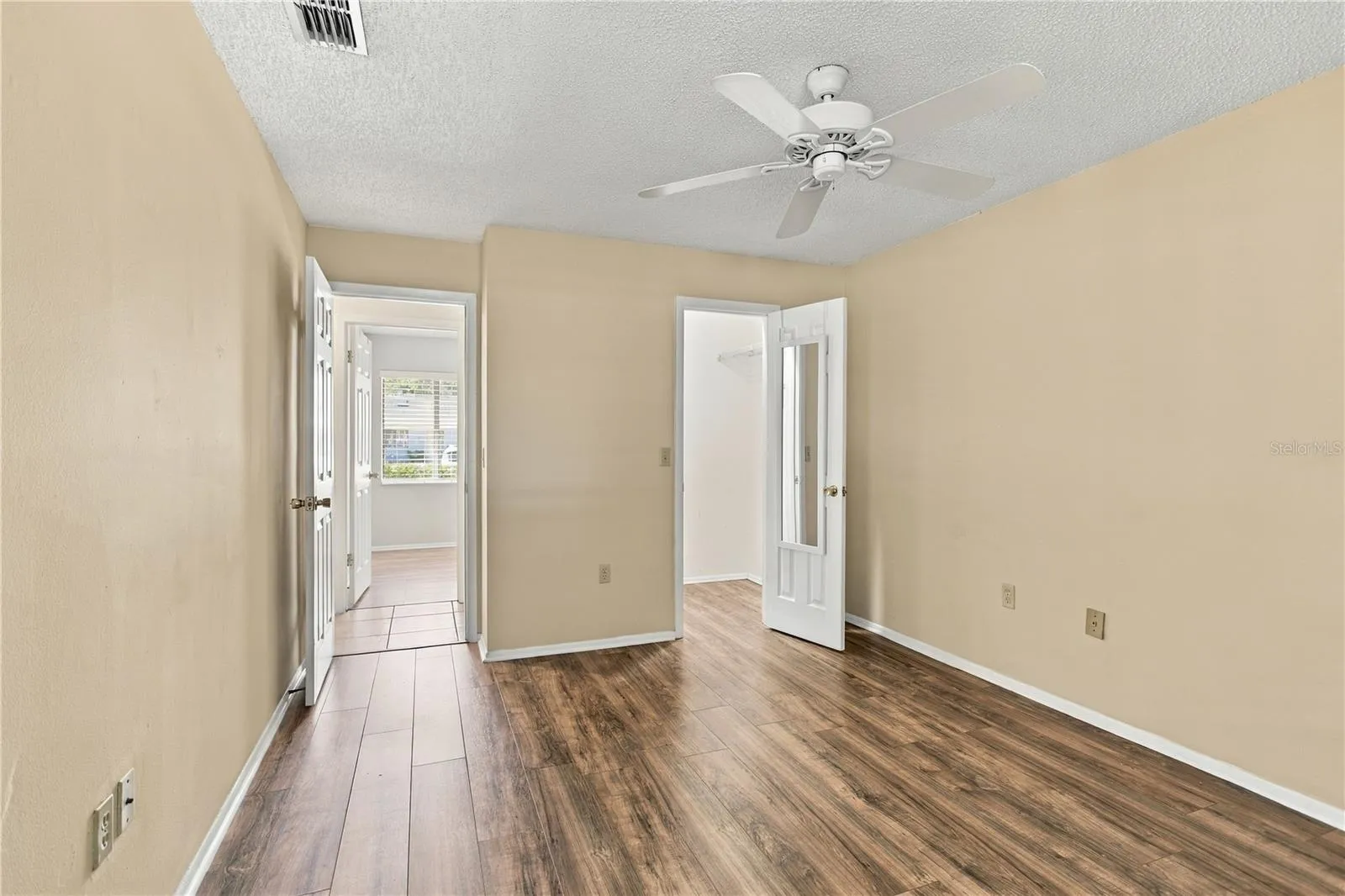 Primary Bedroom with walk-in closet, laminate floors and freshly painted neutral walls.
