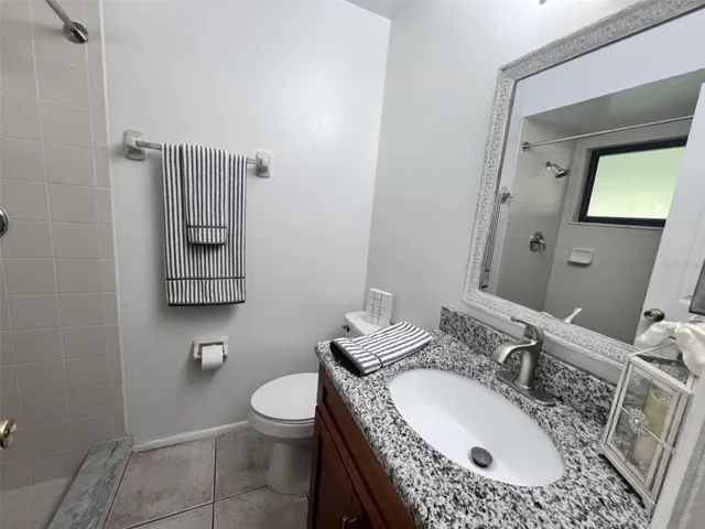 Primary bathroom with updated vanity, granite countertop and walk-in shower