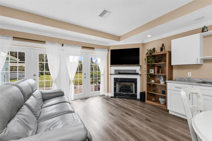 Open living room and kitchen with fireplace with French doors leading to paver patio