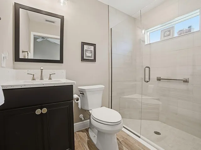GUEST BATH WITH QUARTZ COUNTERTOPS AND FRAMELESS GLASS SHOWER DOOR.