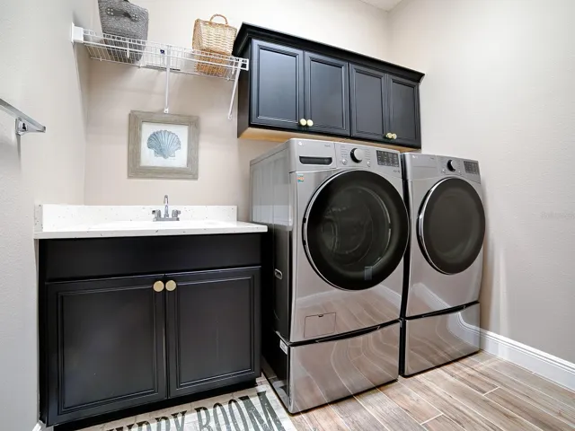 THE LAUNDRY ROOM IS IN THE HALLWAY THAT LEADS TO THE 2ND GUEST SUITE. QUARTZ COUNTERTOPS, BUILT-IN SINK AND EXTRA CABINETS FOR MORE STORAGE SPACE.  THE FRONT LOAD WASHER AND DRYER DO CONVEY.