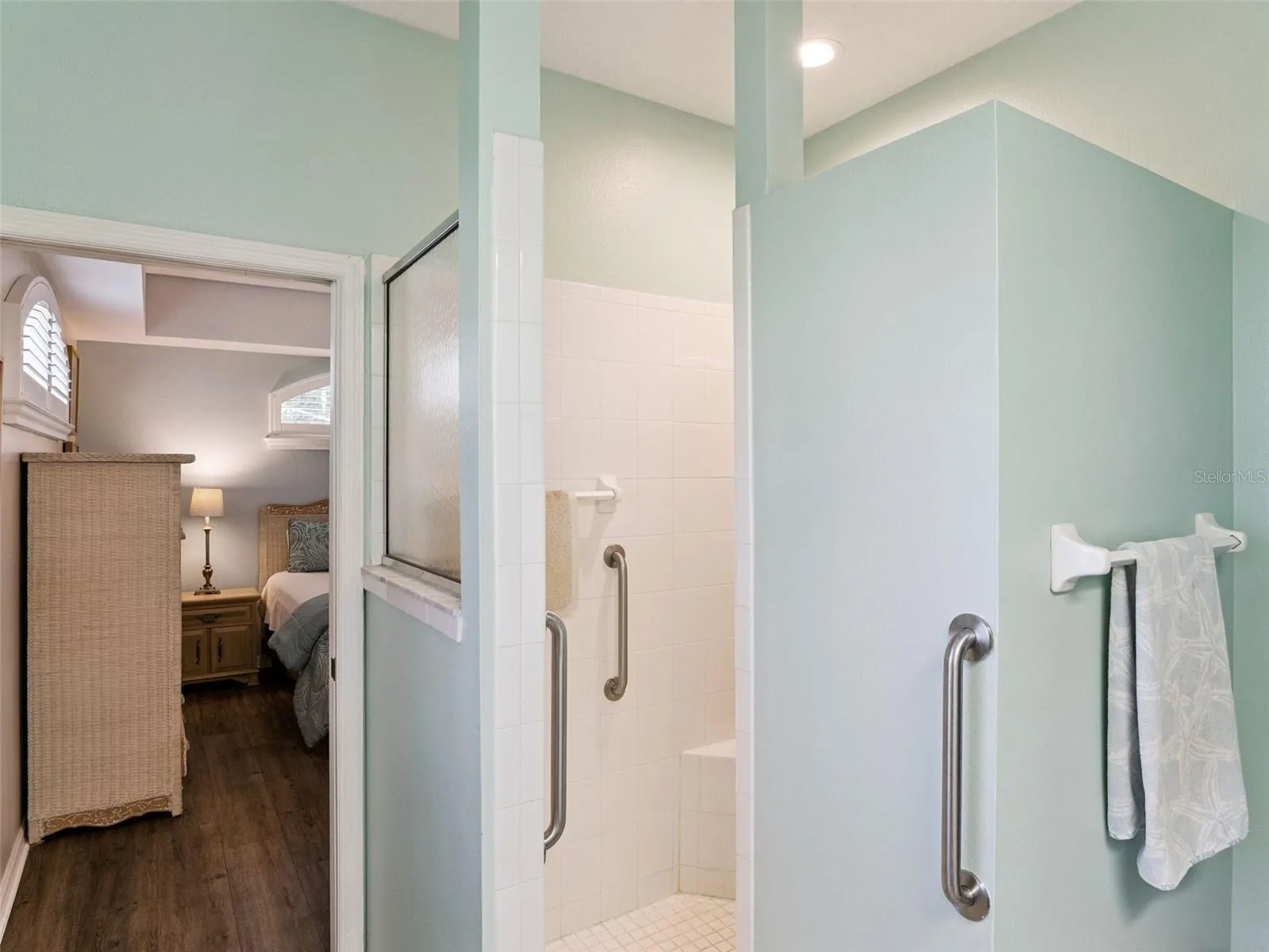 Primary en suite ~ the walk-in shower has a built-in bench and grab bars for safety.