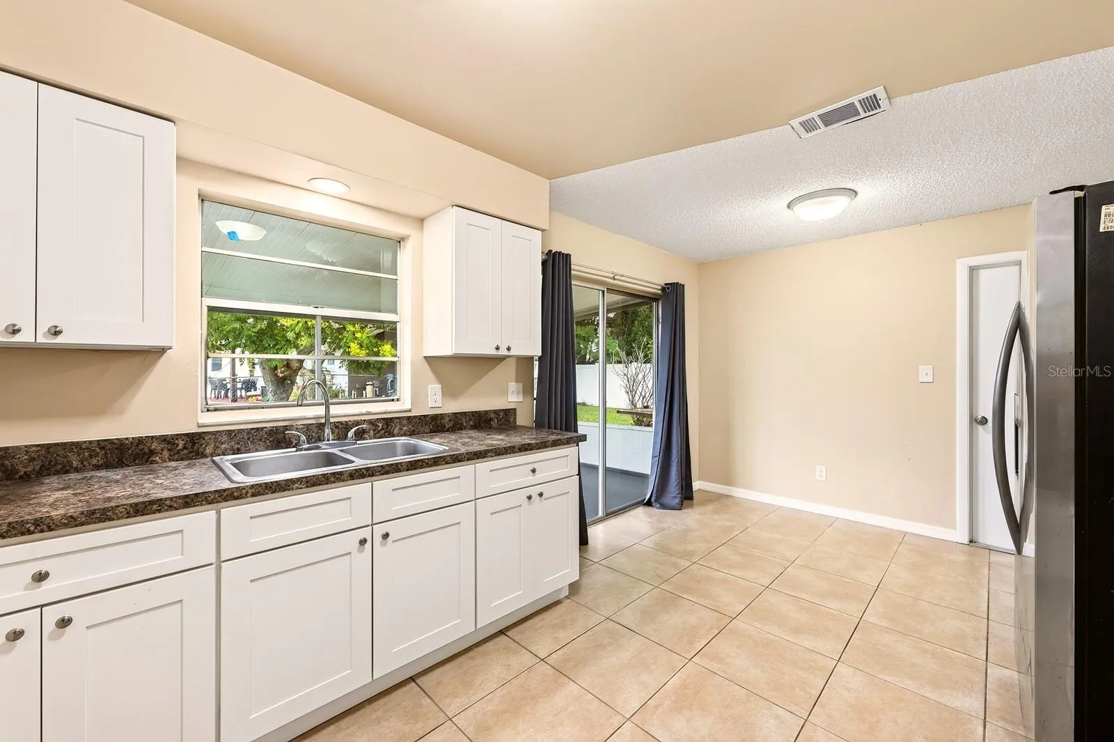 A SUNNY EAT-IN DINING AREA features sliding glass doors that open to the SCREENED AND ENCLOSED BACK PORCH.