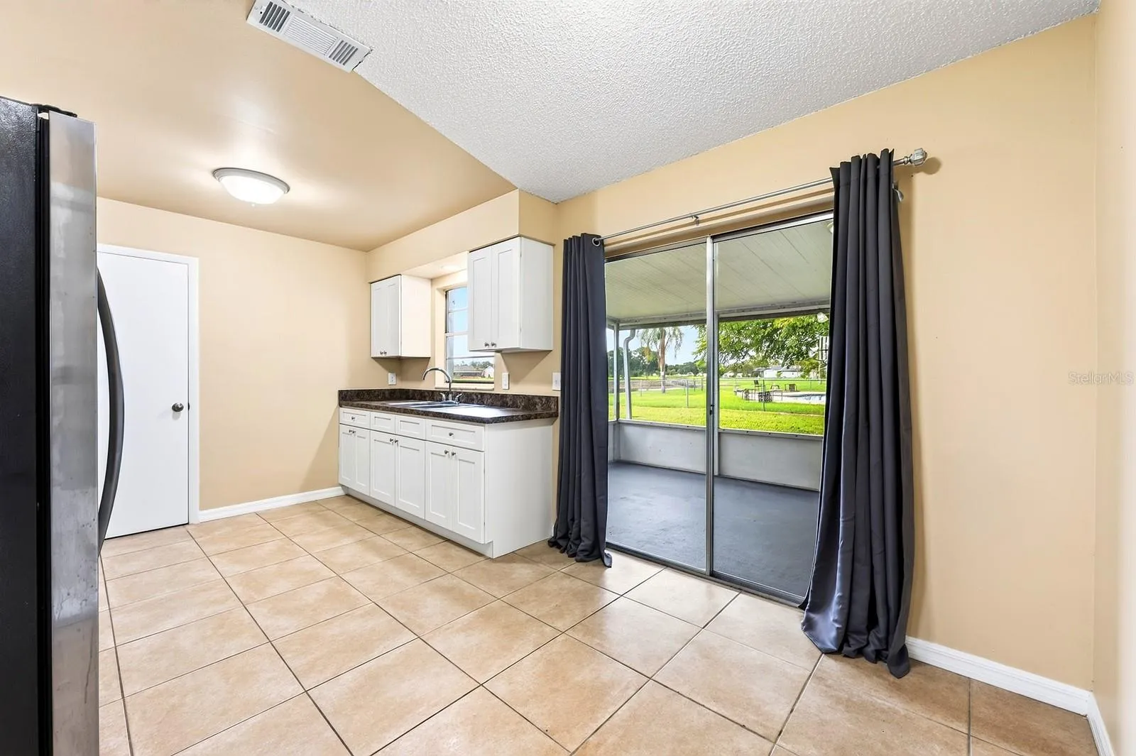 A SUNNY EAT-IN DINING AREA features sliding glass doors that open to the SCREENED AND ENCLOSED BACK PORCH.