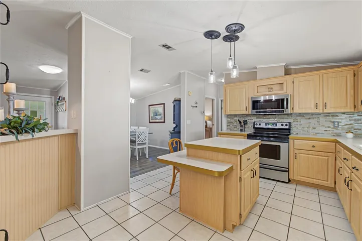 Open kitchen with center island, stainless appliances, and tile floor.